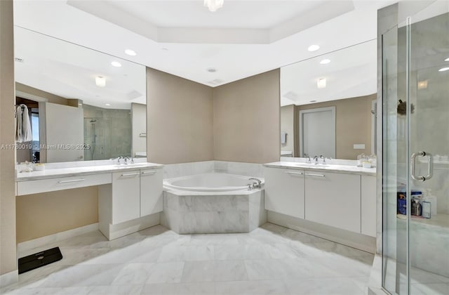bathroom featuring a bath, a raised ceiling, a sink, a shower stall, and two vanities