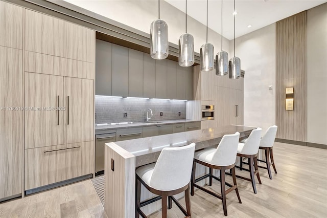 kitchen featuring a center island, oven, modern cabinets, a sink, and a kitchen breakfast bar