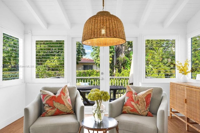 sunroom / solarium with baseboards, beamed ceiling, and wood finished floors