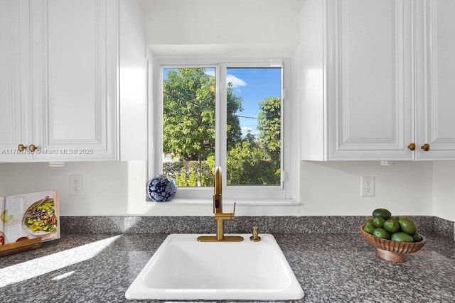 interior details with a sink, dark stone countertops, and white cabinets