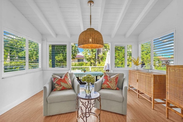 sunroom featuring baseboards, lofted ceiling with beams, and wood finished floors