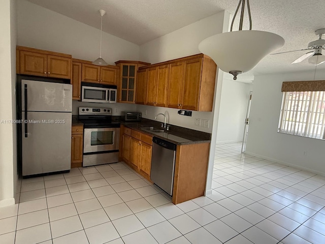 6720 NW 166th Ter Unit 401, Miami Lakes, FL 33014 - kitchen featuring brown cabinetry, dark countertops, a textured ceiling, a sink, and stainless steel appliances