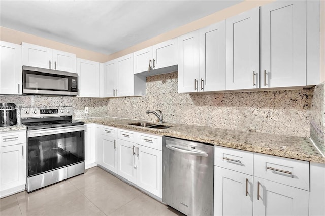 kitchen featuring stainless steel appliances, a sink, light tile patterned floors, and white cabinets
