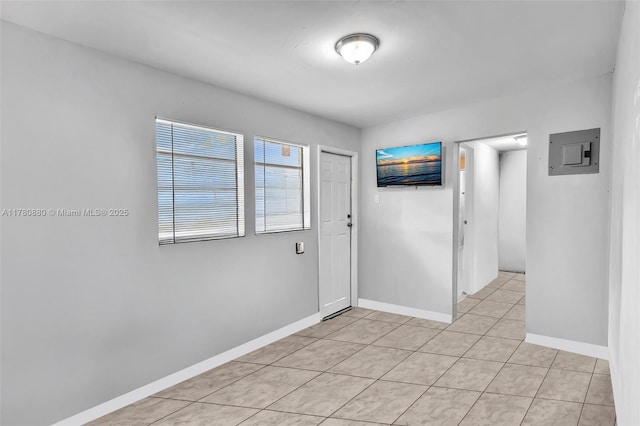 unfurnished room featuring electric panel, light tile patterned flooring, and baseboards