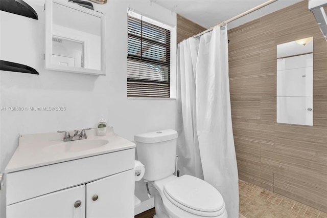 full bathroom with a tile shower, toilet, and vanity