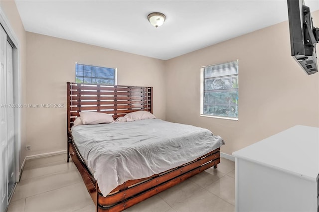 bedroom with a closet, baseboards, and light tile patterned floors