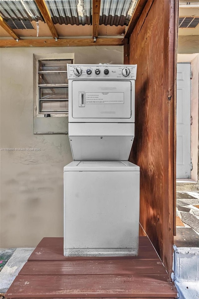 clothes washing area featuring stacked washer and clothes dryer