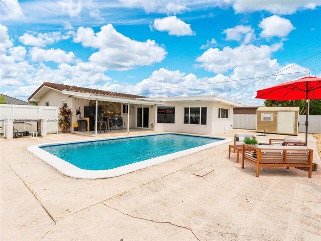 view of swimming pool with a fenced in pool, a shed, a patio area, an outbuilding, and fence