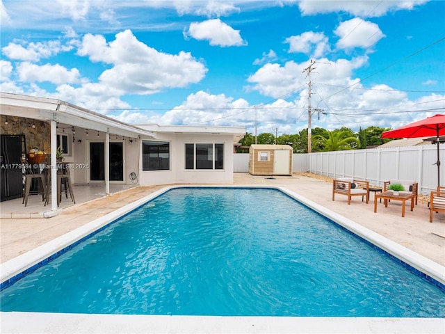 view of swimming pool with a fenced in pool, a patio, a fenced backyard, and an outbuilding