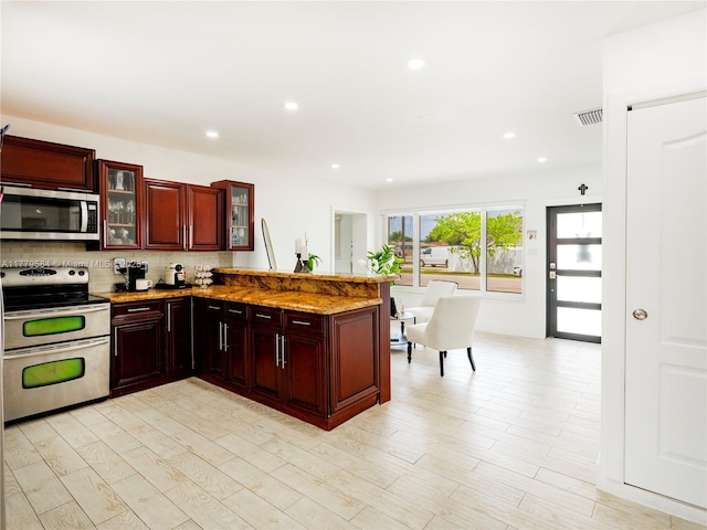 kitchen featuring tasteful backsplash, a peninsula, dark brown cabinets, visible vents, and appliances with stainless steel finishes