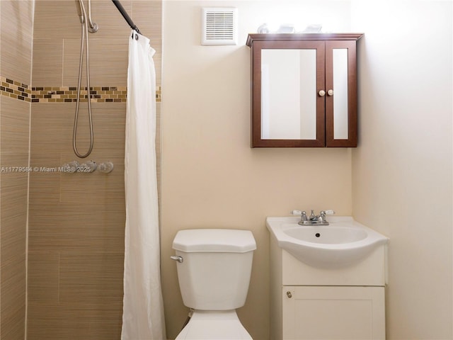 bathroom featuring visible vents, toilet, tiled shower, and vanity