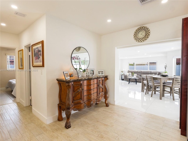 hallway with light wood-style floors, baseboards, visible vents, and recessed lighting