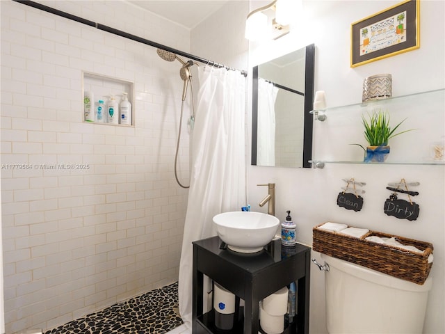 bathroom featuring a tile shower, a sink, and toilet