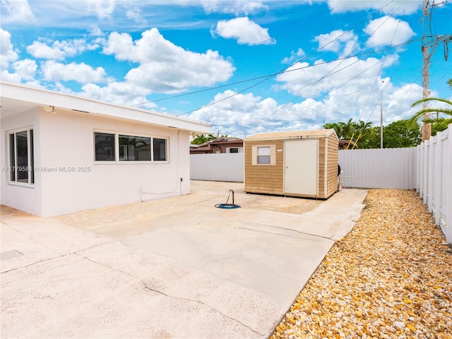 view of patio / terrace featuring a fenced backyard, an outdoor structure, and a shed