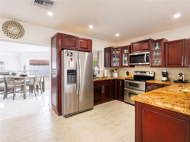kitchen featuring appliances with stainless steel finishes, decorative backsplash, a sink, and visible vents