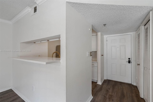 hall featuring dark wood-type flooring, visible vents, baseboards, and a textured ceiling