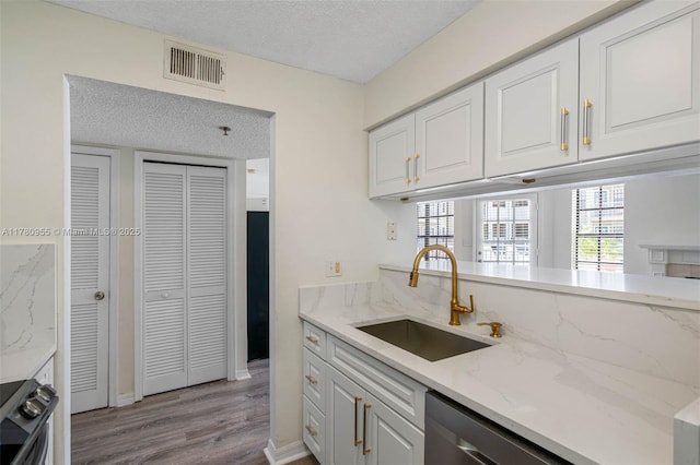 kitchen featuring a textured ceiling, white cabinets, visible vents, stainless steel appliances, and a sink
