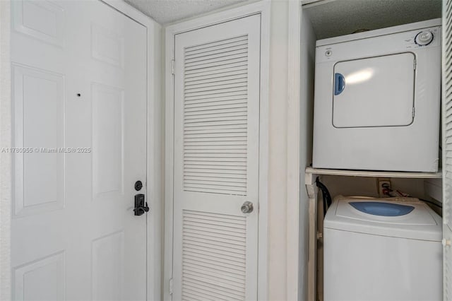 laundry room with stacked washer and dryer, laundry area, and a textured ceiling