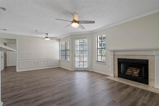 unfurnished living room with crown molding, a fireplace, a textured ceiling, a ceiling fan, and wood finished floors