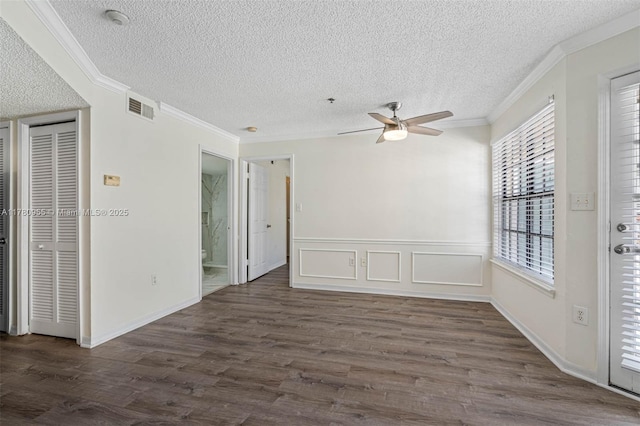 spare room with crown molding, ceiling fan, dark wood-style floors, and visible vents