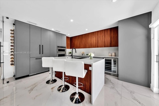 2021 SW 23rd St, Miami, FL 33145 - kitchen featuring wine cooler, modern cabinets, a sink, light countertops, and a kitchen bar
