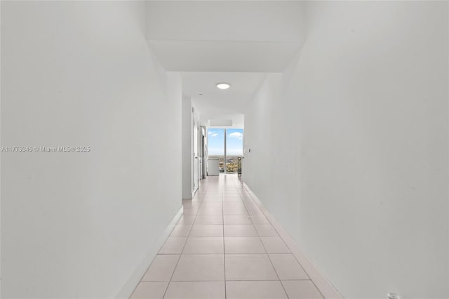 hall featuring baseboards and light tile patterned floors