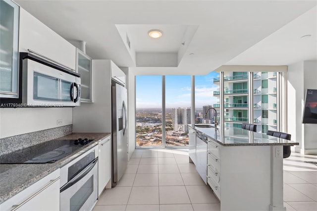 kitchen featuring a sink, dark stone counters, light tile patterned flooring, visible vents, and appliances with stainless steel finishes