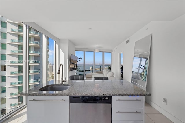 kitchen featuring white cabinets, dark stone countertops, visible vents, stainless steel dishwasher, and a sink