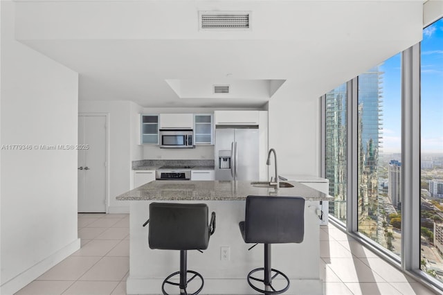 kitchen with visible vents, light tile patterned floors, a wall of windows, a sink, and appliances with stainless steel finishes