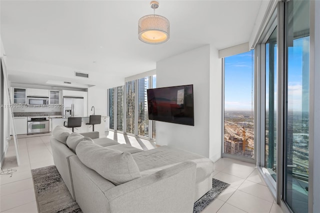 living area featuring a wall of windows, visible vents, and light tile patterned floors