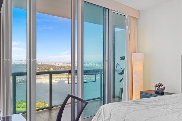 bedroom with expansive windows, tile patterned floors, and a water view