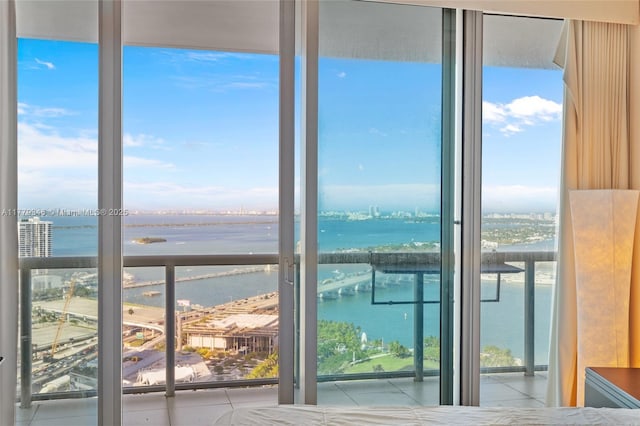 entryway with floor to ceiling windows, tile patterned floors, and a water view