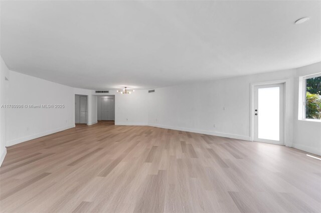 1301 NE 191st St Unit F117, Miami, FL 33179 - unfurnished living room featuring visible vents, light wood-style flooring, and baseboards