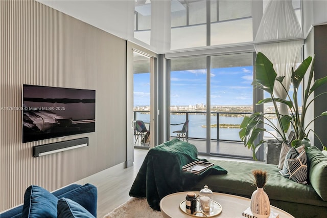living area featuring light wood-type flooring, floor to ceiling windows, and a water view