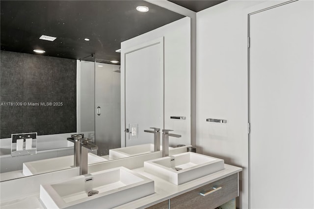 bathroom with walk in shower, double vanity, recessed lighting, and a sink