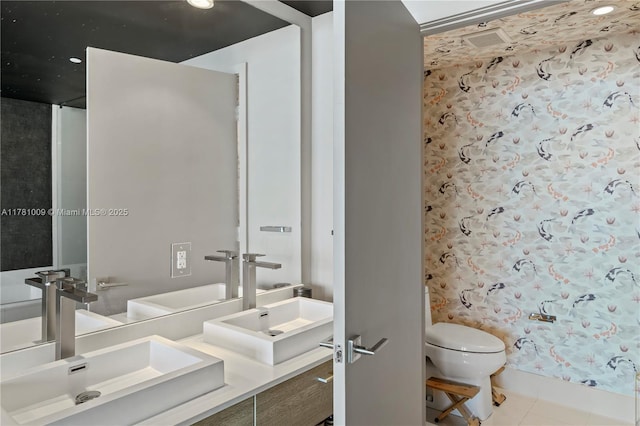 full bathroom featuring double vanity, toilet, a sink, and tile patterned flooring
