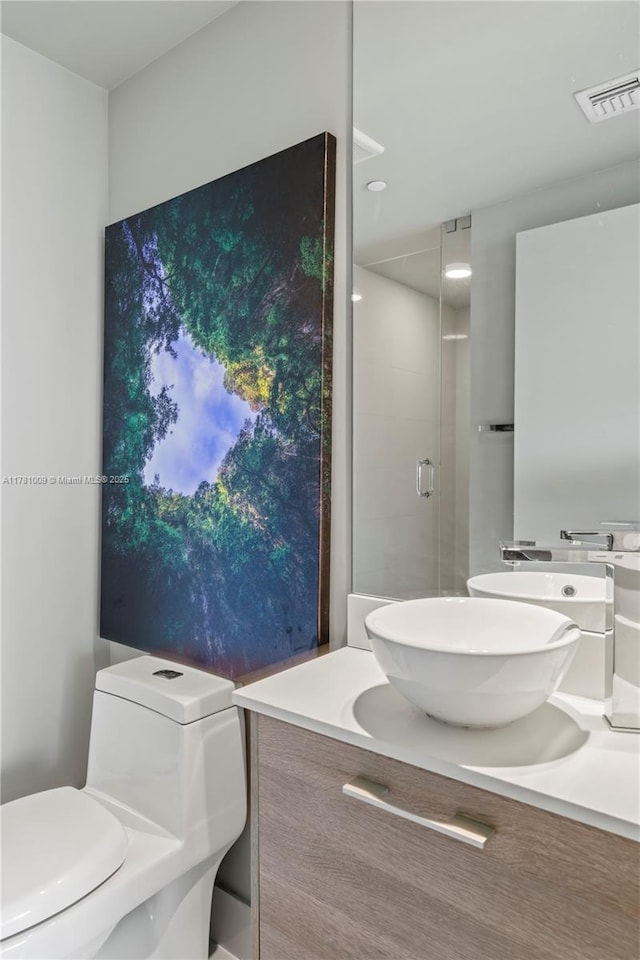 full bath featuring vanity, a stall shower, toilet, and visible vents