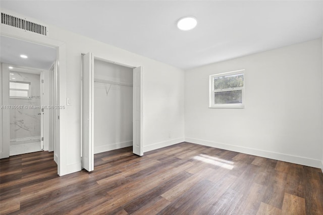 unfurnished bedroom with dark wood-type flooring, visible vents, baseboards, and a closet