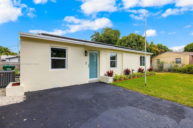 ranch-style home with cooling unit, stucco siding, a patio area, a front yard, and fence