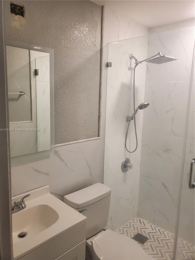 full bath with a textured wall, vanity, toilet, tile walls, and a marble finish shower