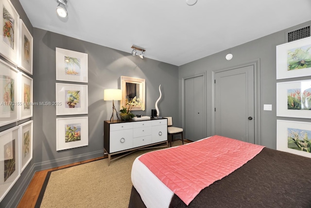 bedroom featuring baseboards, wood finished floors, and visible vents