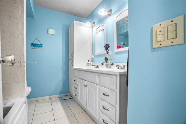 bathroom with baseboards, toilet, double vanity, a bathtub, and tile patterned flooring