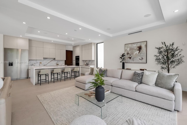 living room with recessed lighting and a tray ceiling