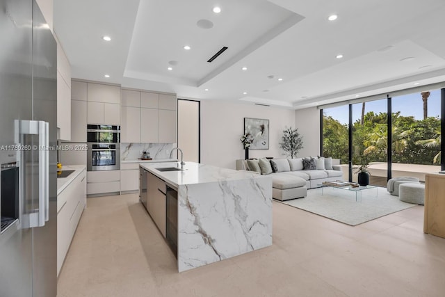 kitchen featuring modern cabinets, recessed lighting, a raised ceiling, a sink, and appliances with stainless steel finishes