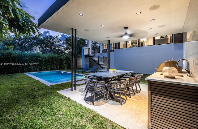 pool featuring a lawn, a patio area, stairway, a sink, and outdoor dining space