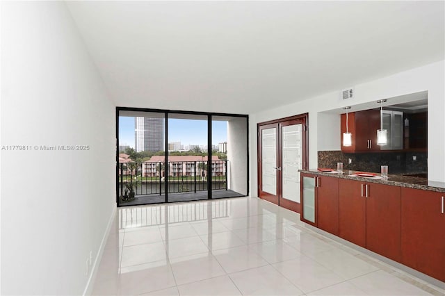 kitchen featuring tasteful backsplash, baseboards, dark stone countertops, light tile patterned floors, and french doors