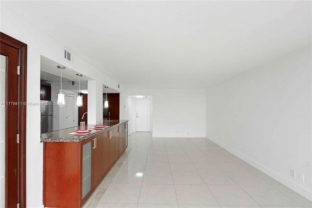 kitchen featuring light tile patterned floors, freestanding refrigerator, visible vents, a sink, and hanging light fixtures