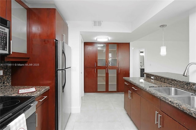 kitchen featuring glass insert cabinets, hanging light fixtures, visible vents, a sink, and stainless steel appliances