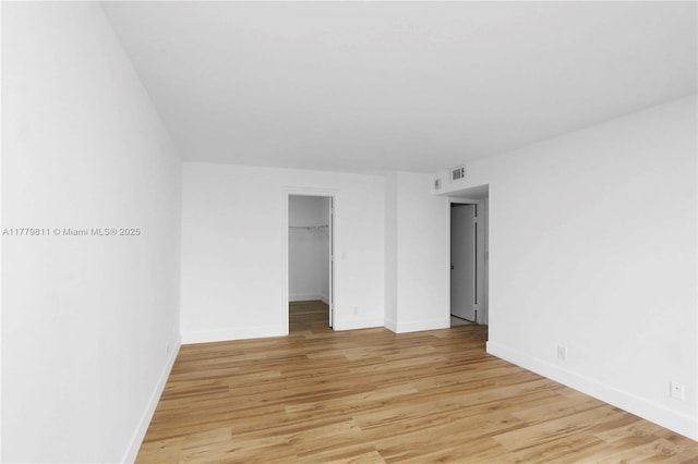 spare room featuring light wood-style flooring, baseboards, and visible vents