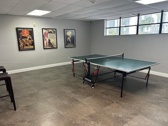 rec room featuring a paneled ceiling and baseboards